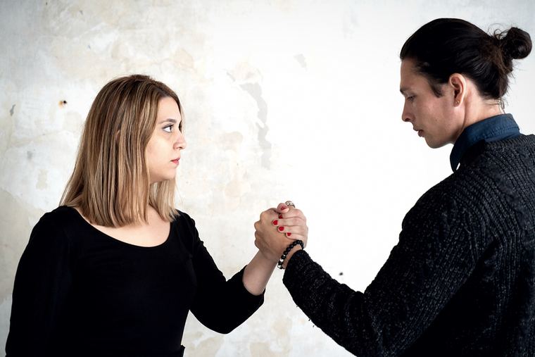 The duo facing one another, hands joined, seen wide.