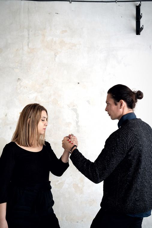 Eyes lowered, hands still held between them.